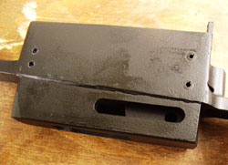Visible here are the four through pins that hold the block in the mag well. The block is also retained by epoxy. The slot for the magazine catch is also clearly visible, as is the slot’s protrusion into the mag well.