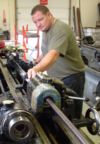 A McGowen machinist guides a drill on a manual lathe.