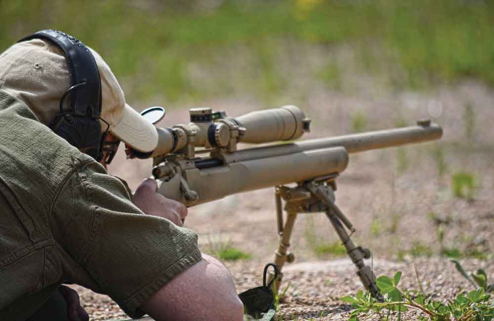Shooter lining up a long-distance shot with scoped rifle.