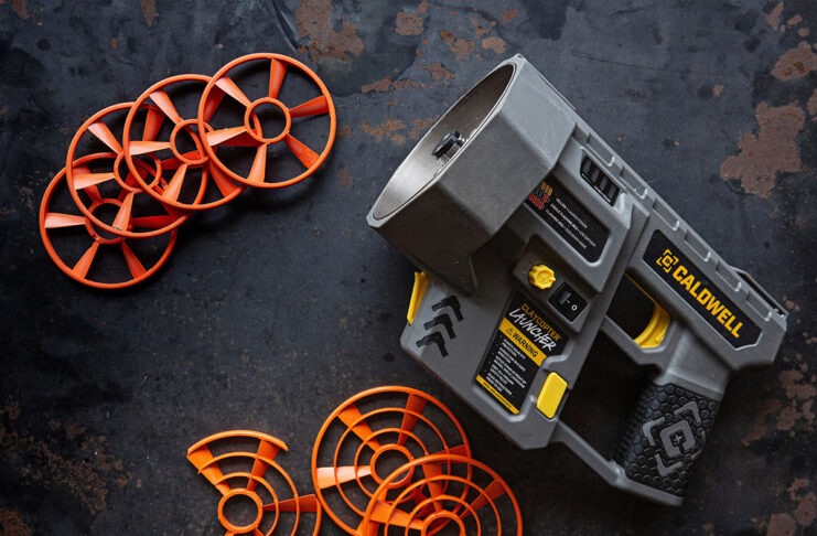 Caldwell ClayCopter Review: The Next Evolution Of Shotgun Fun A Caldwell ClayCopter Hand-Held Thrower next to its special clays on a black background.