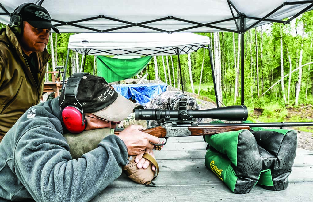 Here, a hunter is taught to shoot properly from a bench. This position contradicts the way many shooting benches are actually built. By changing the bench to be square, we can see the results of our own shots downrange without the aid of a spotter.
