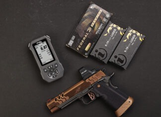 Double Alpha EDGE Shot Timer: The Timer Never Lies The Double Alpha EDGE Shot Timer sitting next to a Kimber pistol and three boxes of ammo on a black background.