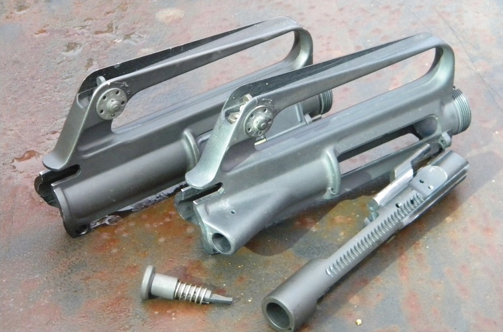 The forward assist, or bolt-closure device, is located on the right rear of the upper receiver. It uses a ratchet action to force the bolt forward into battery. The upper receiver (pictured top) is an early model without an external forward assist.