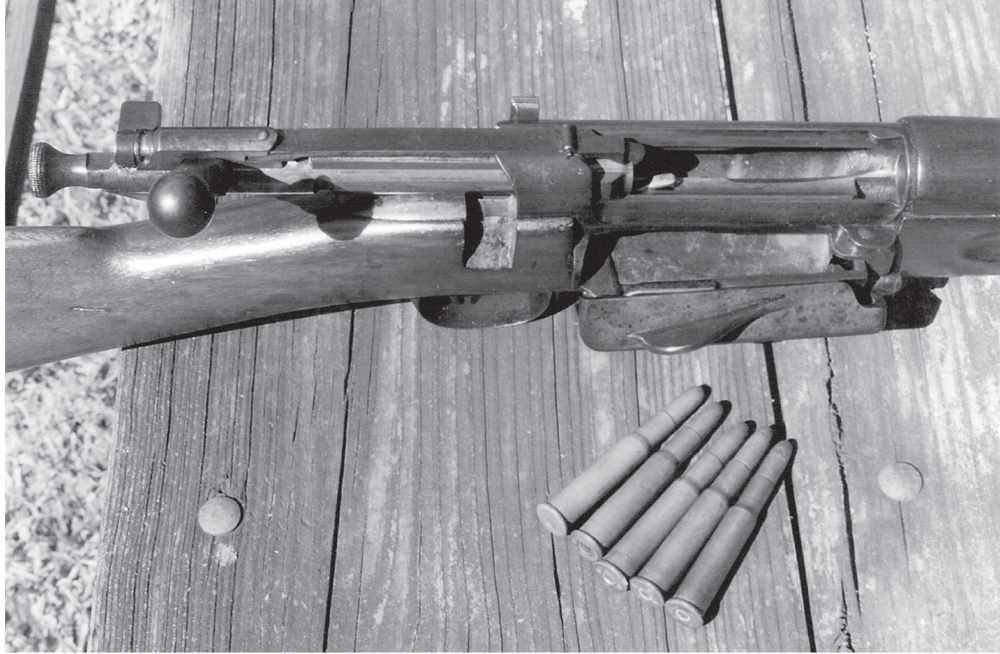 The unique Krag magazine, shown here with the right-side cover open, held five cartridges. The American Krag used the .30-40 Krag cartridge, and five original military cartridges are shown near the rifle. The Krag magazine could be loaded with the bolt either open or closed.