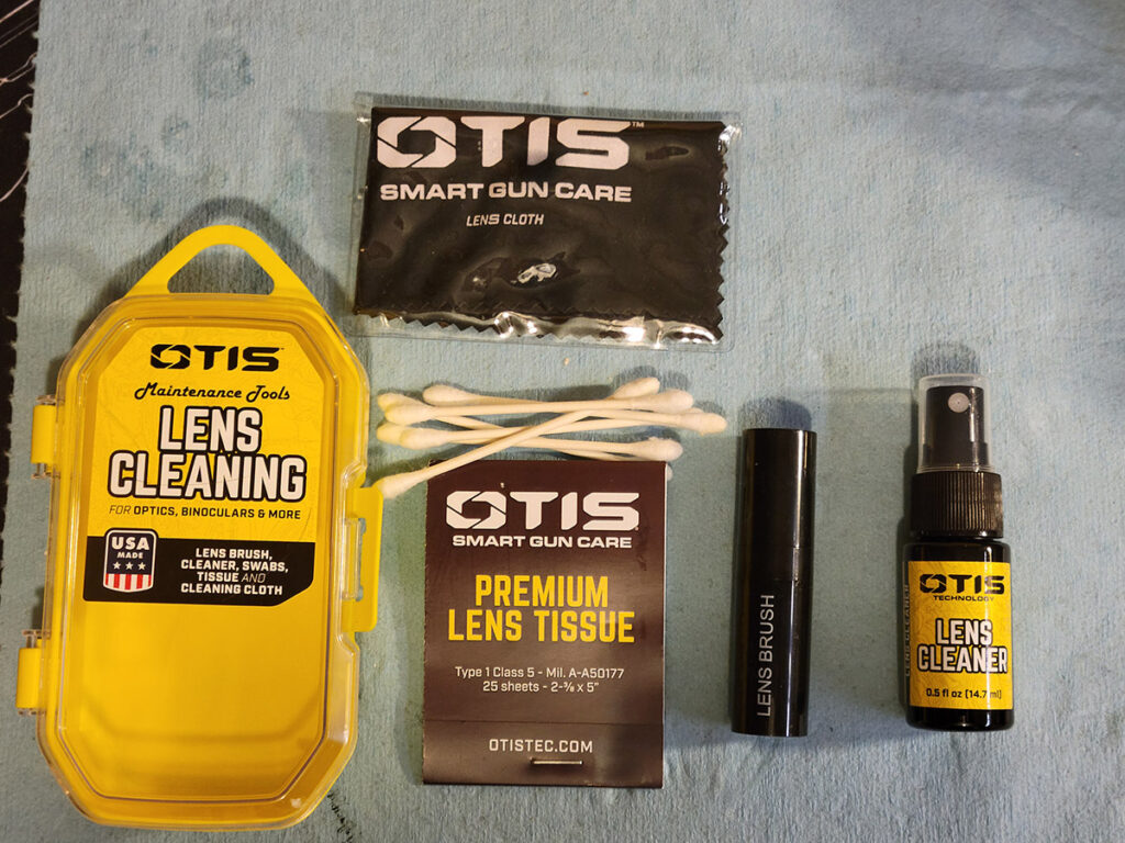 The contents of the Otis Lens Cleaning Kit laid out on a blue shop towel.