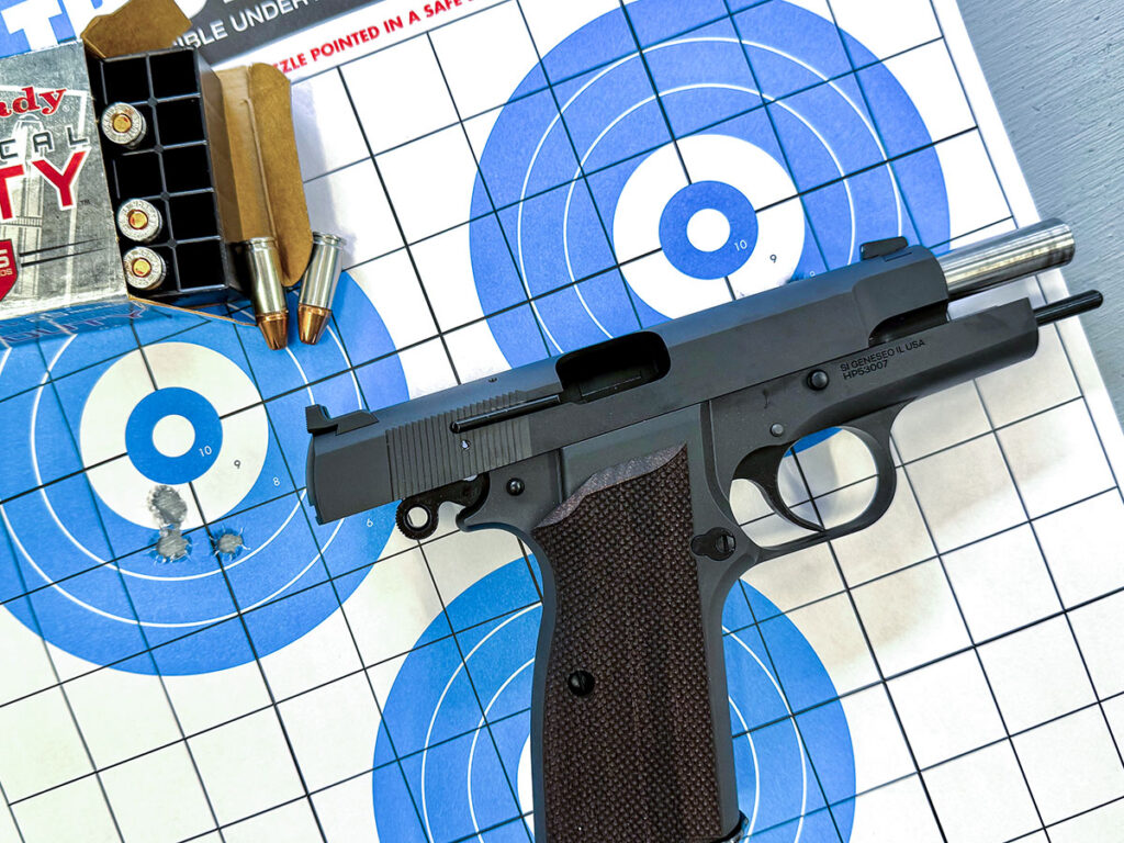 The Springfield SA-35 4-Inch with its slide locked laying on a shot target and a box of Hornaday Critical Duty ammo.