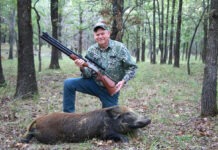 Air Rifle Hunting: Under Tremendous Pressure The author kneeling while holding a Dragon Claw II air rifle with a boar he's just harvested in the woods.