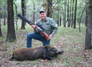 Air Rifle Hunting: Under Tremendous Pressure The author kneeling while holding a Dragon Claw II air rifle with a boar he's just harvested in the woods.