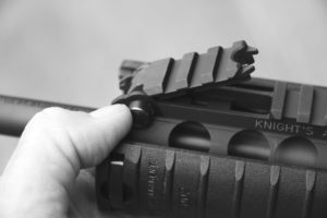 The front sight is hinged, and you only need press the button.