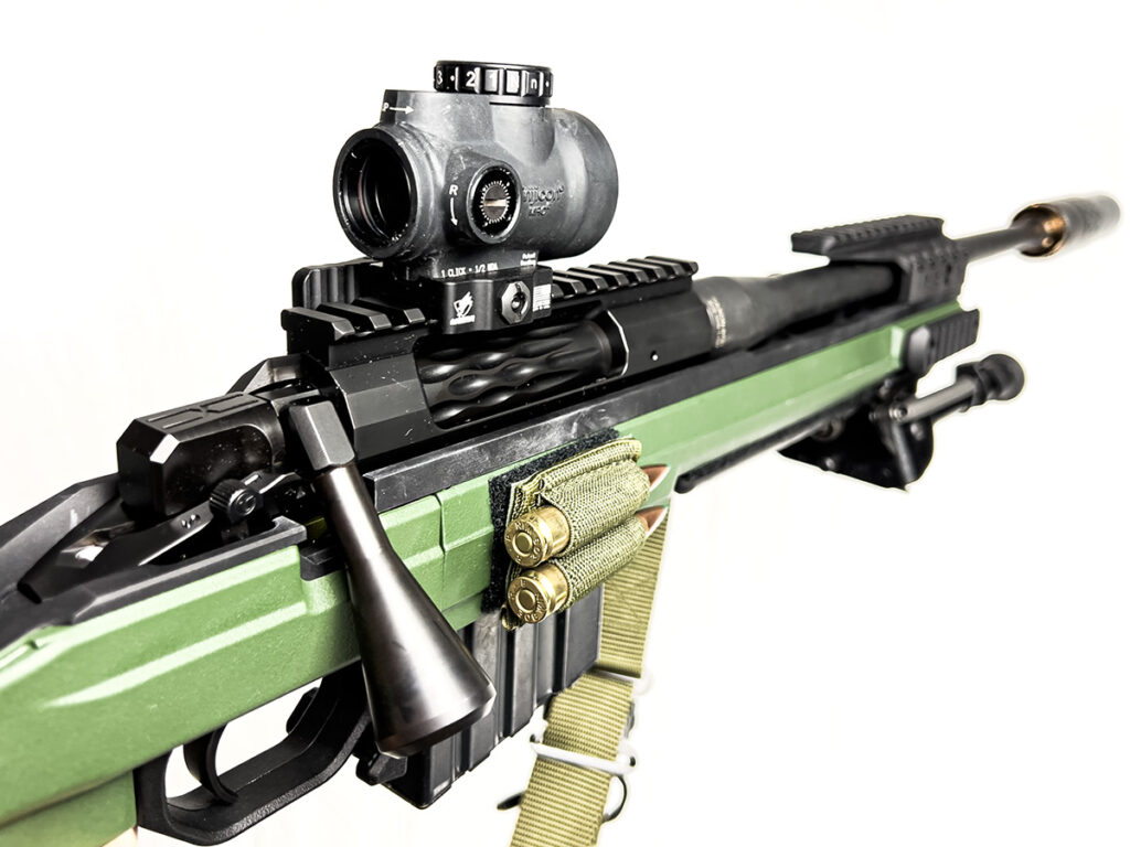 A Faxon FX7 scout rifle build equipped with a red dot sight and a suppressor.