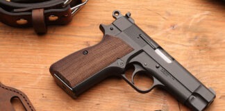 First Look: Springfield Armory SA-35 4” A Springfield SA-35 4" pistol laying on a wooden table next to a loaded magazine, a leather holster and a belt.