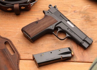 First Look: Springfield Armory SA-35 4” A Springfield SA-35 4" pistol laying on a wooden table next to a loaded magazine, a leather holster and a belt.