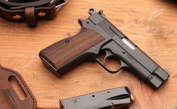 First Look: Springfield Armory SA-35 4” A Springfield SA-35 4" pistol laying on a wooden table next to a loaded magazine, a leather holster and a belt.